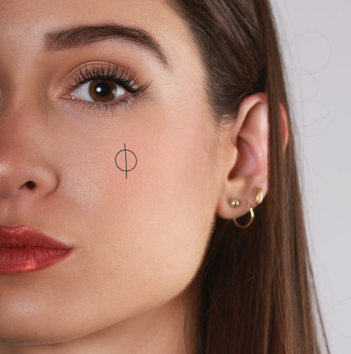 tatouage ephemere spirituel sur la joue style minimaliste et equilibre